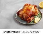 Small photo of Homemade Lemon and Herb Rotisserie Chicken on a Plate on a gray surface, side view. Copy space.