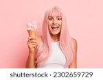 Beautiful girl in white top holds ice cream cornet in one hand, standing isolated on pink studio background, very happy face expression, copy space