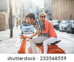 glamorous  young couple riding  a vintage scooter in the street, man wears a hat and woman has a topknot and sunglasses