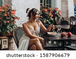Beautiful smiling brunette girl having lunch in a street cafe, sitting at a table and eating Italian pasta. Advertising, commercial design.