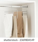 Small photo of Closet with Pant Hanger, Clothes Hanging on Stainless Steel Hanger in a Modern, Bright, and White Dressing Room.