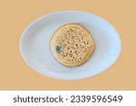 Small photo of Mouldy uncooked crumpet on a white plate
