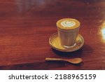Small photo of A cup of coffee latte art Rosetta on wooden table.