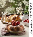Small photo of Easter traditional bread, austrian ostern zopf, greek tsoureki and red eggs on a table with linen tablecloth with spring window view, still life
