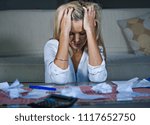 attractive worried and desperate blond woman calculating domestic money expenses doing paperwork and bank bills accounting with calculator suffering stress in financial problem and depression