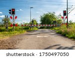 Guarded railroad crossing with closed barriers, red warning light and cross of Saint Andrew.