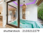 Small photo of Outdoor hot tub in alcove with sliding door neon lights and wicker basket light fixture