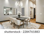 Small photo of Elegant interior image of a dining room with black steel table soft tone curved back chairs swirling light fixture orchid and area rug contemporary home