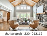 Living room interior with vaulted ceiling with wood cedar panelling stone fireplace brown leather armchairs coffee table and area rug natural brown tones