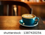 Coffee in blue cup on wooden table in cafe with lighting background