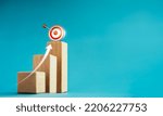 Small photo of Shining rise up arrow shoot up towards the goal, 3d target icon on the top of wooden cube blocks, bar graph chart steps, business growth process, technology trend, economic improvement concepts.