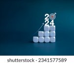 Small photo of 2024 year number with target icon and rise up arrow on white blocks as a graph steps on blue background. New year trends, action plan, profit, business growth process, economic improvement concepts.