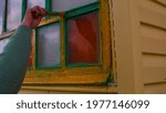 Small photo of Close up of unrecognizable person paints window with yellow paint on street. Concept of renovation and revivification territory.