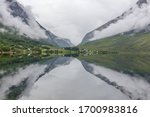 A mystical fjord with dark clouds in Norway with mountains and fog hanging over the water in a beautiful monochrome blue color. selective focus