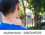 Small photo of Men have neck pain, shoulder pain, at the park health concept. Trapeziums muscle and holding right hand on muscle, swelling and inflammation of left rotatory cuff muscle