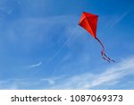 A red kite flying against a...