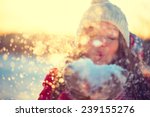 Beauty Winter Girl Blowing Snow in frosty winter Park. Outdoors. Flying Snowflakes. Sunny day. Backlit. Joyful Beauty young woman Having Fun in Winter Park. Defocused