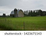 Small photo of Large Gambrel Barn with Silo on a Rainy Day in a Green Pasture