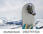 Small photo of a snowboard stuck in the snow and ski goggles hanging on it. Concept to illustrate ski admission fee.