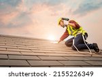 Small photo of Technician in shirt and jeans wear helmet safety suit hand use screwdriver tool install repair C-Pack roof on high work place.Workers work at heights with full safety suits on construction sites.