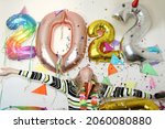 lonely young woman celebrating new year 2022 at home quarantine. smiling girl wiith hands up. big number balloons. silvester party. december 31. lockdown. party decoration. confetti falling. january 1