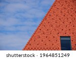 clay tile roof with steep slope in red brown color. roof window or skylight. metal ice and snow guard in square pattern. snow breaker. modern new construction concept. bright blue sky and white clouds