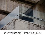 Small photo of glass railing panel and balustrade above stone panel. balcony railing. laminated tempered safety glass. construction and building industry concept. stainless steel glass brackets.