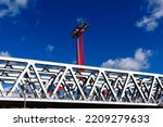 steel railway bridge closeup in perspective view. red steel tower with solar panels. blue sky with white clouds. truss beams with triangular shape members. structural design and engineering. 
