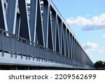 steel railway bridge closeup. diminishing perspective view. blue sky with white clouds. truss girder beams with triangular shaped members. structural design and engineering concept. structural design.
