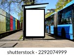 Small photo of bus shelter at bus stop. white poster and commercial ad space display lightbox. base for mockup. outdoors image. blank ad panel. glass design. urban street setting. green background with spring trees