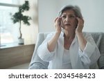 Small photo of Elderly senior woman suffering from migraines and headaches, memory lapses and sleep difficulties. A depressed, melancholy 70-year-old woman has long covid symptoms.