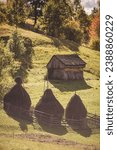 Small photo of A haystacks and wooden barn in the farmyard on the Romanian Carpathian village. A stack of dry grass in the mountains. Landscape with three hayricks in Apuseni Mountains,Transylvania,Romania.