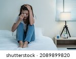 Asian beautiful depression girl crying in tears sit on bed in bedroom. Attractive unhappy young woman feeling sad lonely and upset with life problem and hold tissue on hands in dark night room at home