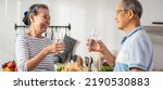 Small photo of Asian senior elderly couple drink a glass of water in kitchen at home. Mature older thirsty grandparent holding clean mineral natural in cup after waking up and sip in morning for health care in house