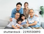 Small photo of Portrait of Asian loving family and kid daughter stroking cat in house. Happy family, Attractive happy multi generation sitting on sofa spendind free leisure time together with their pet at home.