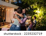 Young Asian woman visit the family during party outdoors in the garden. Attractive diverse group of people having dinner, eating foods, celebrate weekend reunion gathered together at the dining table