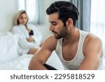 Caucasian young couple sit on bed with painful after fight argument. New marriage man and woman crying and feel heartbroken for their quarrel conflict in bedroom. Family problem-separation concept.