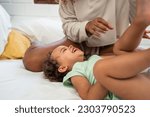 Small photo of African loving mom play with cute baby girl child on bed in bedroom. Happy family, attractive beautiful young mother ticklish on toddler daughter enjoying activity relationship in morning in house.