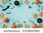 Halloween holiday frame with party decorations of pumpkins, bats, ghosts, spiders on blue background top view. Happy halloween card in flat lay style.