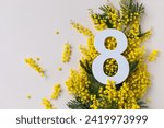 Small photo of 8 march greeting card with fresh branch of memosa spring flowers and number eight top view. International Women Day holiday background.