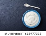 Greek yogurt in blue bowl on black table top view.