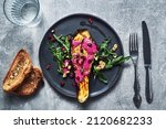 Small photo of Roasted eggplant garnished with beetroot sauce and pomegranate seeds and walnuts with rocket salad on black plate. Roasted eggplant with beetroot sauce vegetarian and vegan food