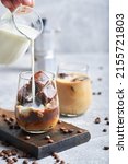 Small photo of Ice coffee in glass. Ice coffee served in glass with coffee ice cubes and milk cream on table.