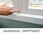 Small photo of Woman hand insulating old windows to prevent warmth heat leak and drafts, preparing house for winter and cold weather