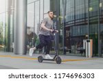 Attractive man riding a kick scooter at cityscape background.