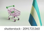 Small photo of An empty metal shopping basket and the flag of the Gabonese Republic on a light background is a concept of consumption and a consumer basket.