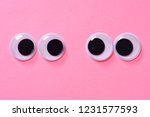 Googly eyes of pair of lovers on rose background. Close up.