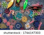 Small photo of Variety of multi-colored examples of tatting lace, shuttles for weaving lace tatting with multi-colored threads and beads on a dark gray stone background. Tatting is a kind of elite needlework.
