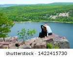 A fit couple sits together on a rock overlooking a beautiful lake as woman runs her hand through her hair. Photo taken in southern Wisconsin.