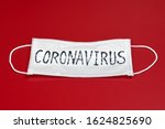 Сoronavirus - COVID-19 - 2019-nCoV, WUHAN virus concept. Surgical mask protective mask with CORONAVIRUS text. Chinese coronavirus COVID-19 outbreak. Red background.